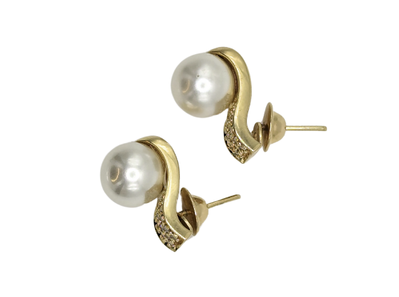 Snuggly huggie earrings in 18k yellow gold set with cream-colored pearls and shiny white diamonds. 