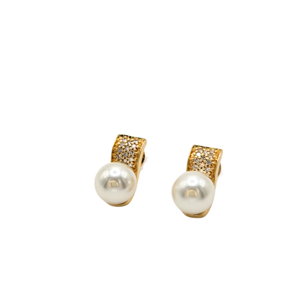 Snuggly huggie earrings in 18k yellow gold set with cream-colored pearls and shiny white diamonds. 